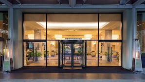 Entrada de hotel con puerta giratoria, puertas de cristal y un interior bien iluminado.
