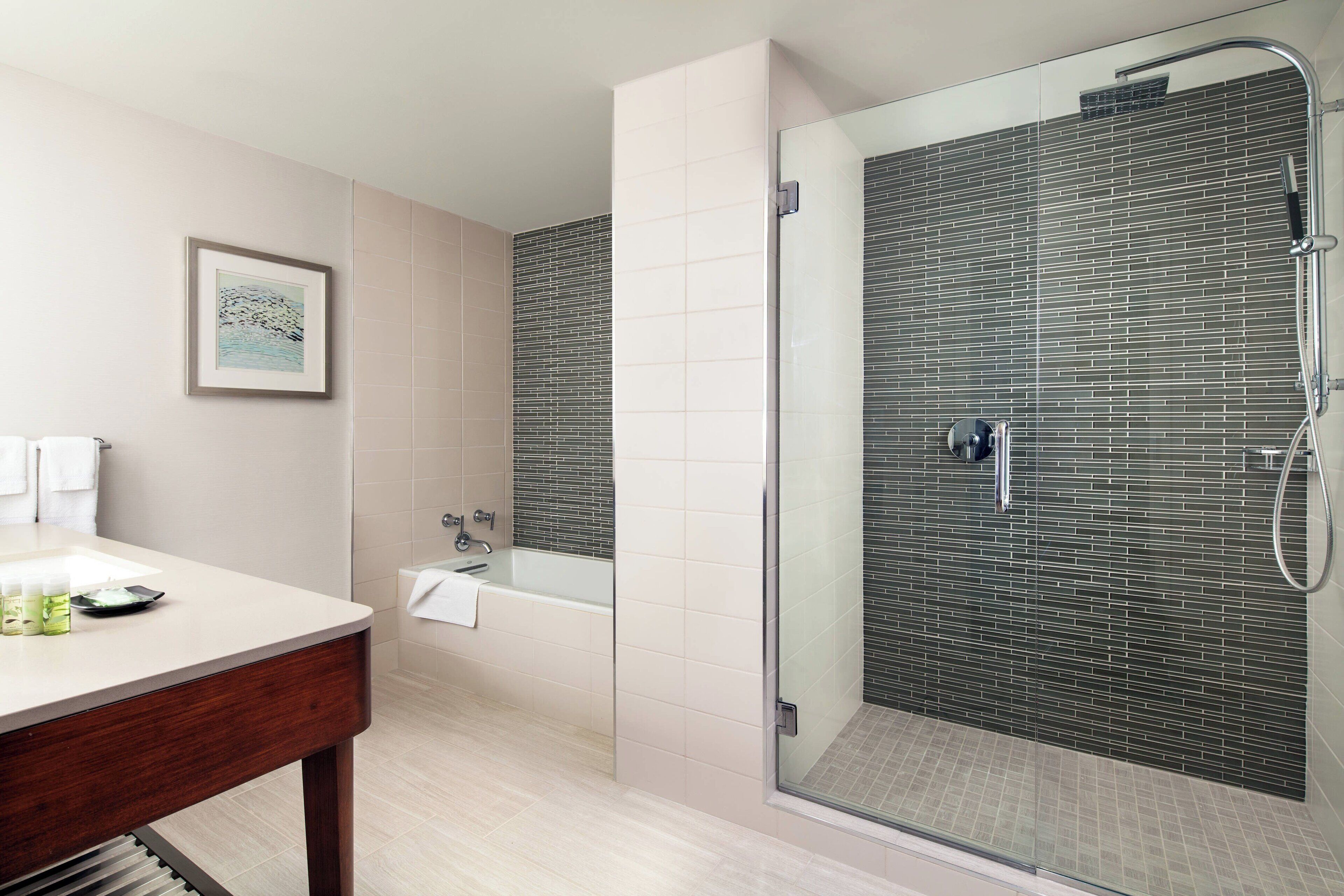 A modern bathroom with a glass-enclosed shower, a bathtub, and a vanity with toiletries.