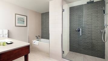 A modern bathroom with a glass-enclosed shower, a bathtub, and a vanity with toiletries.