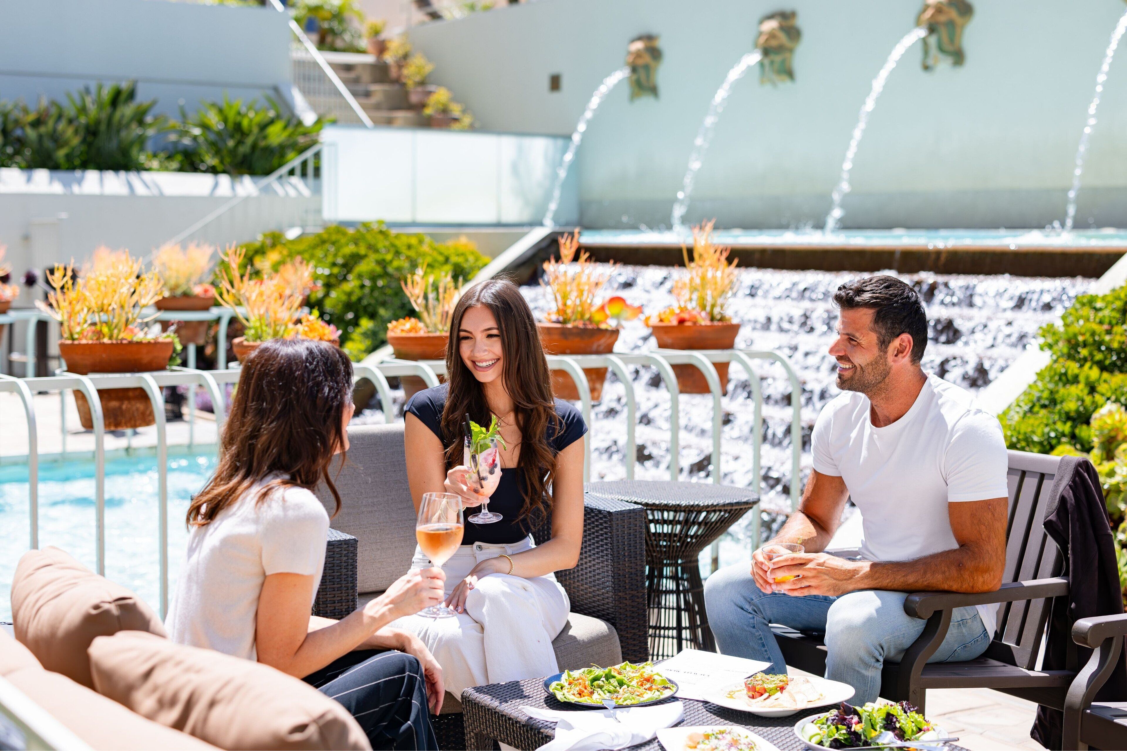 A poolside seating area with a table, chairs, and a dining table with plates and drinks.