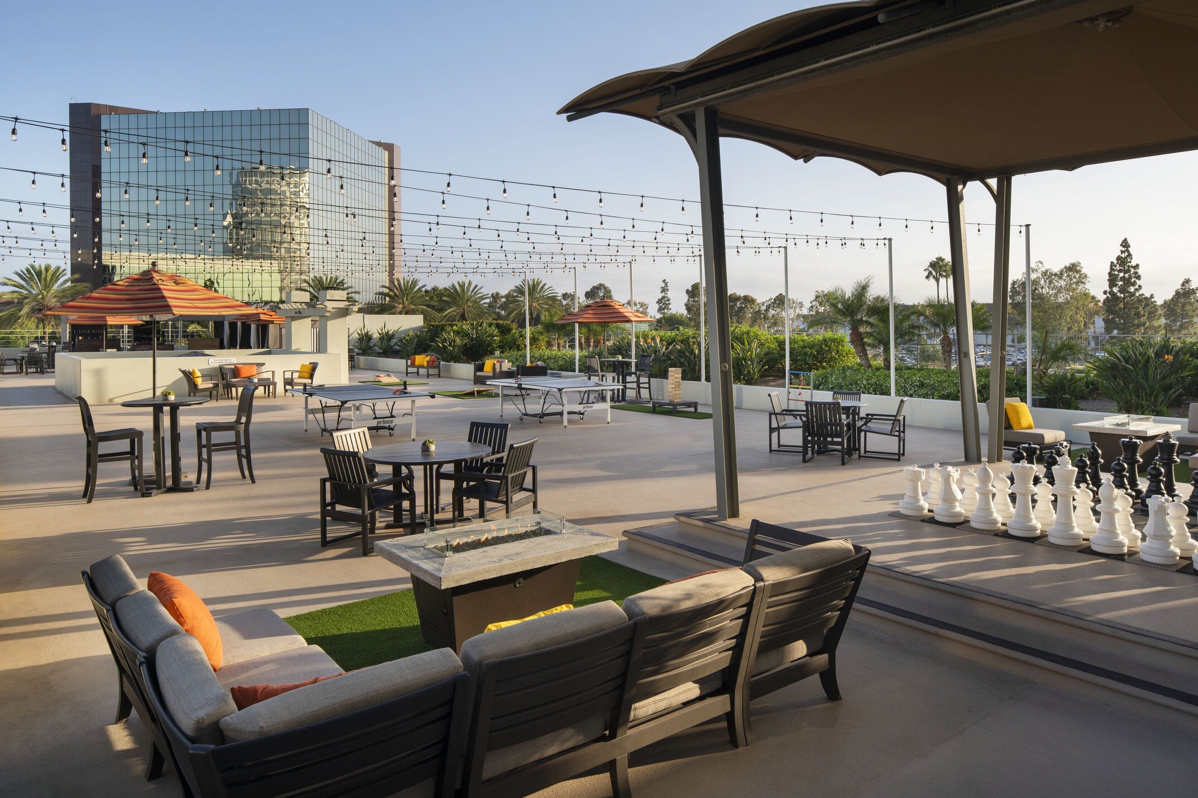 An outdoor seating area with tables and chairs, a fire pit, and a chessboard.
