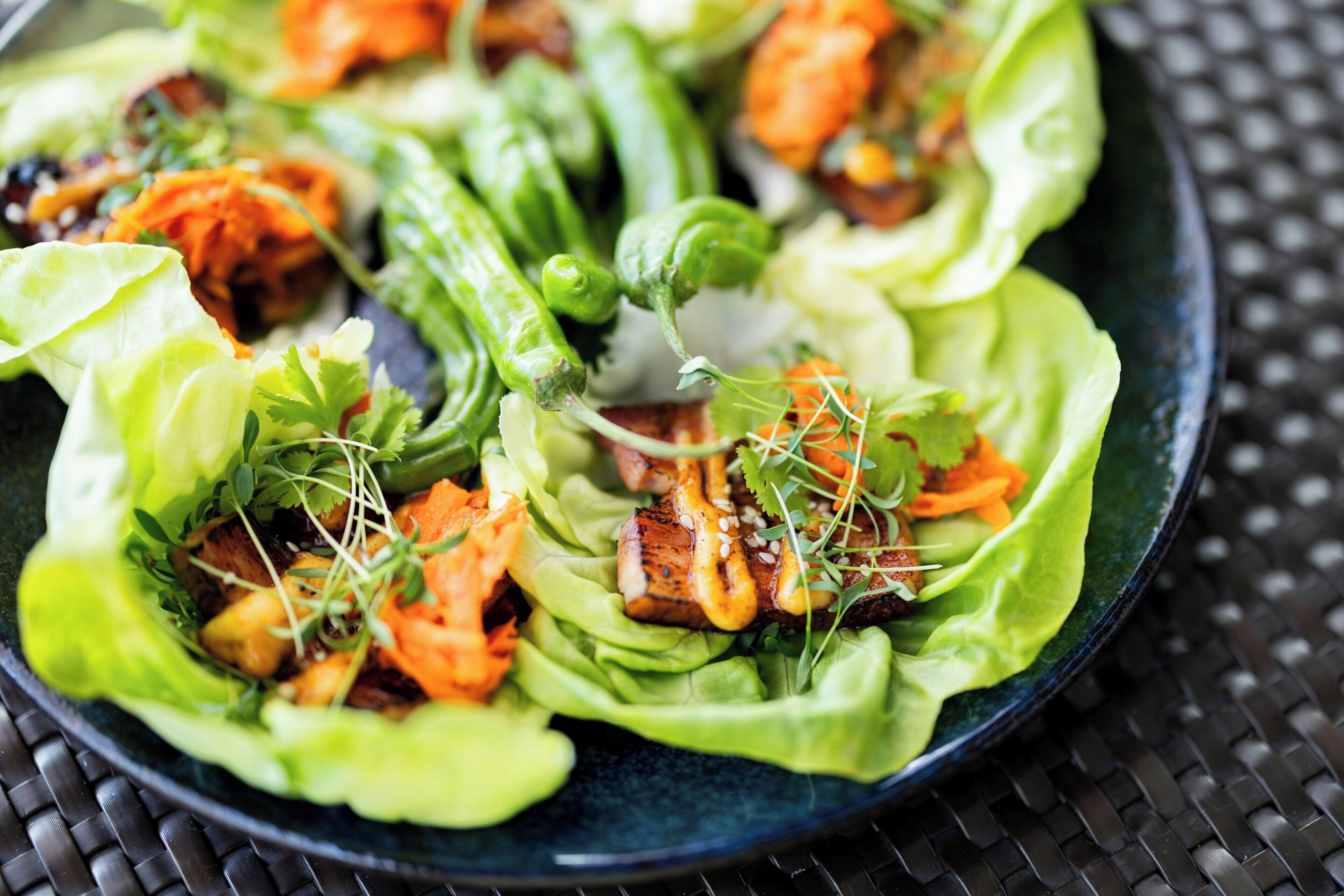 A bowl of salad with lettuce, carrots, and grilled meat.