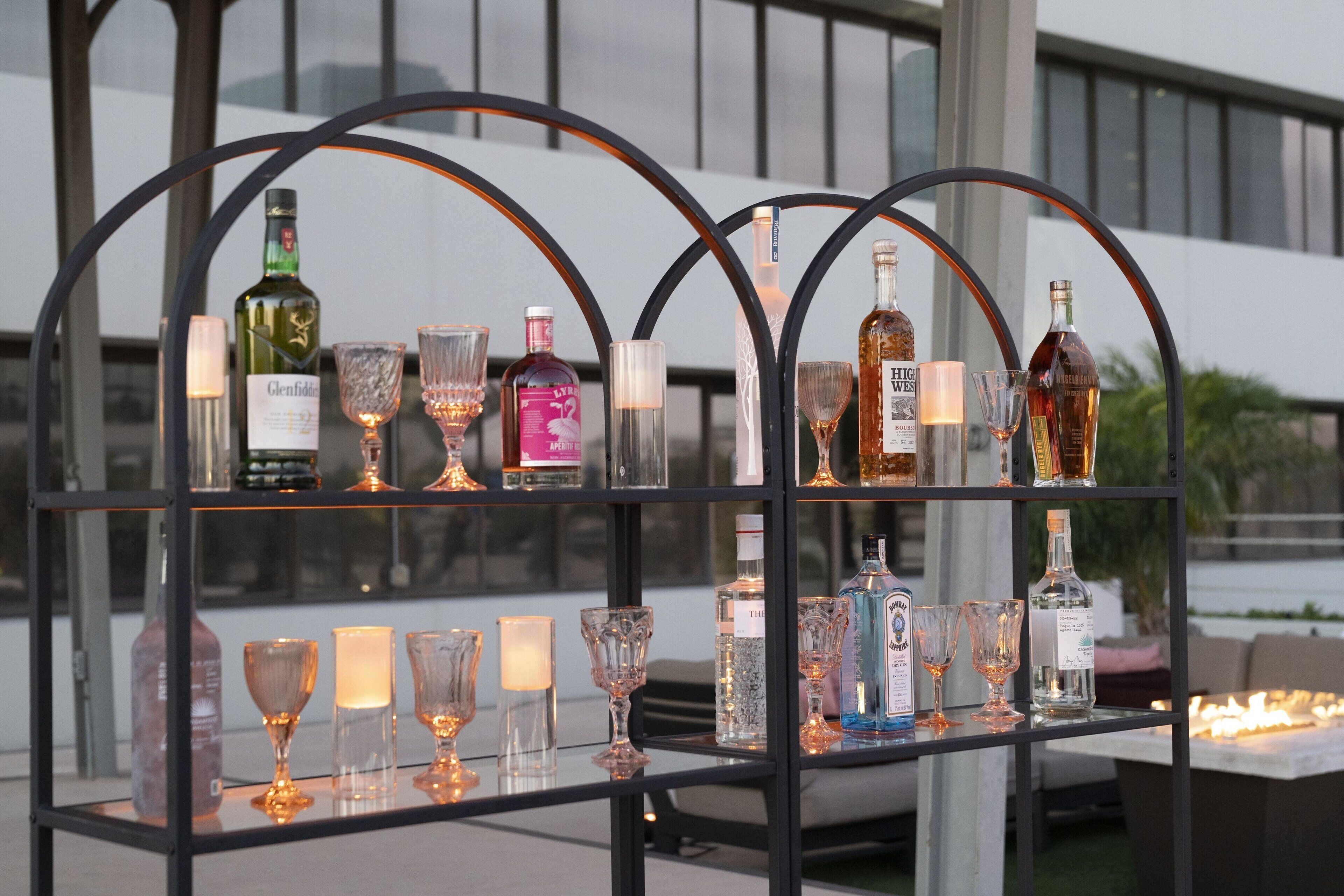 Una mesa de vidrio con varios botellas y vasos, con un moderno edificio de fondo.
