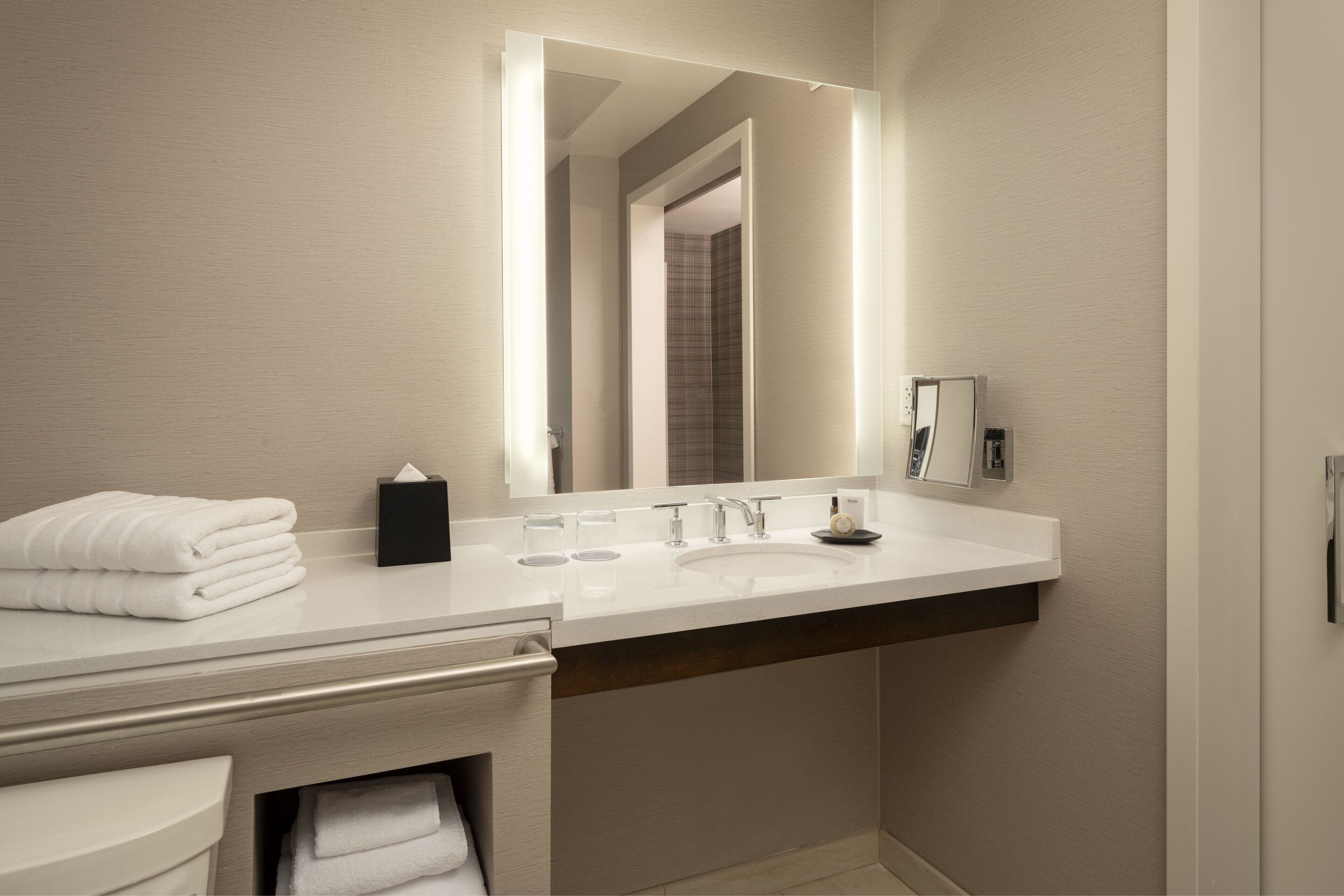 A modern bathroom with a white vanity, a large mirror, and a built-in sink.