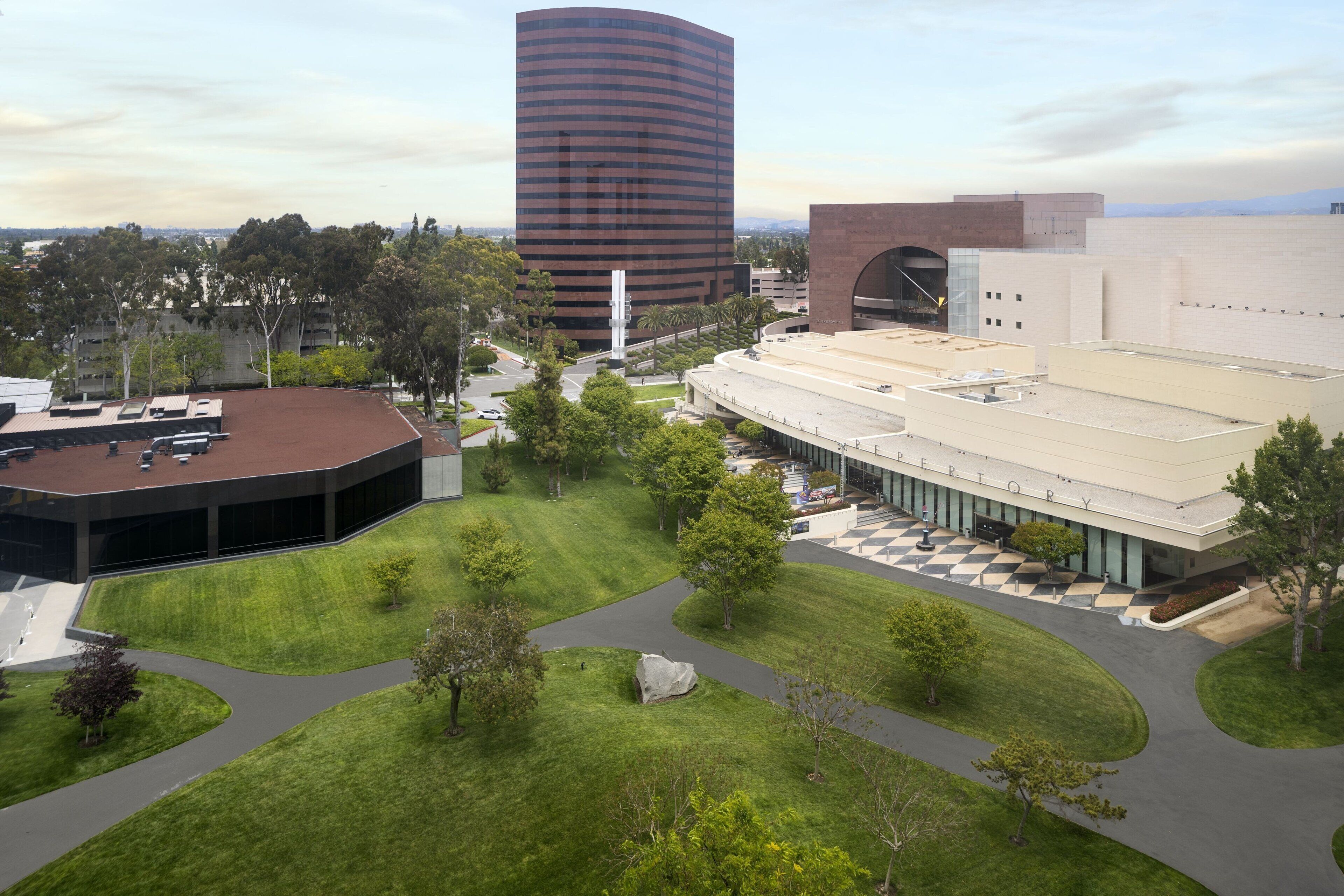 A modern building complex with a central courtyard, a large parking area, and a prominent cylindrical structure.