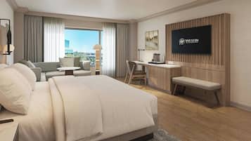 A hotel room with a bed, a desk, a chair, a TV, and a view of the city.