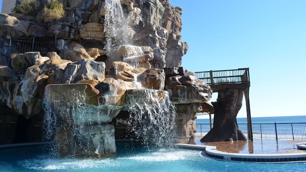 Une piscine agrémentée d’une cascade et entourée de formations rocheuses.