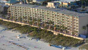 Un hôtel à plusieurs étages, doté de balcons, situé juste à côté d’une plage.