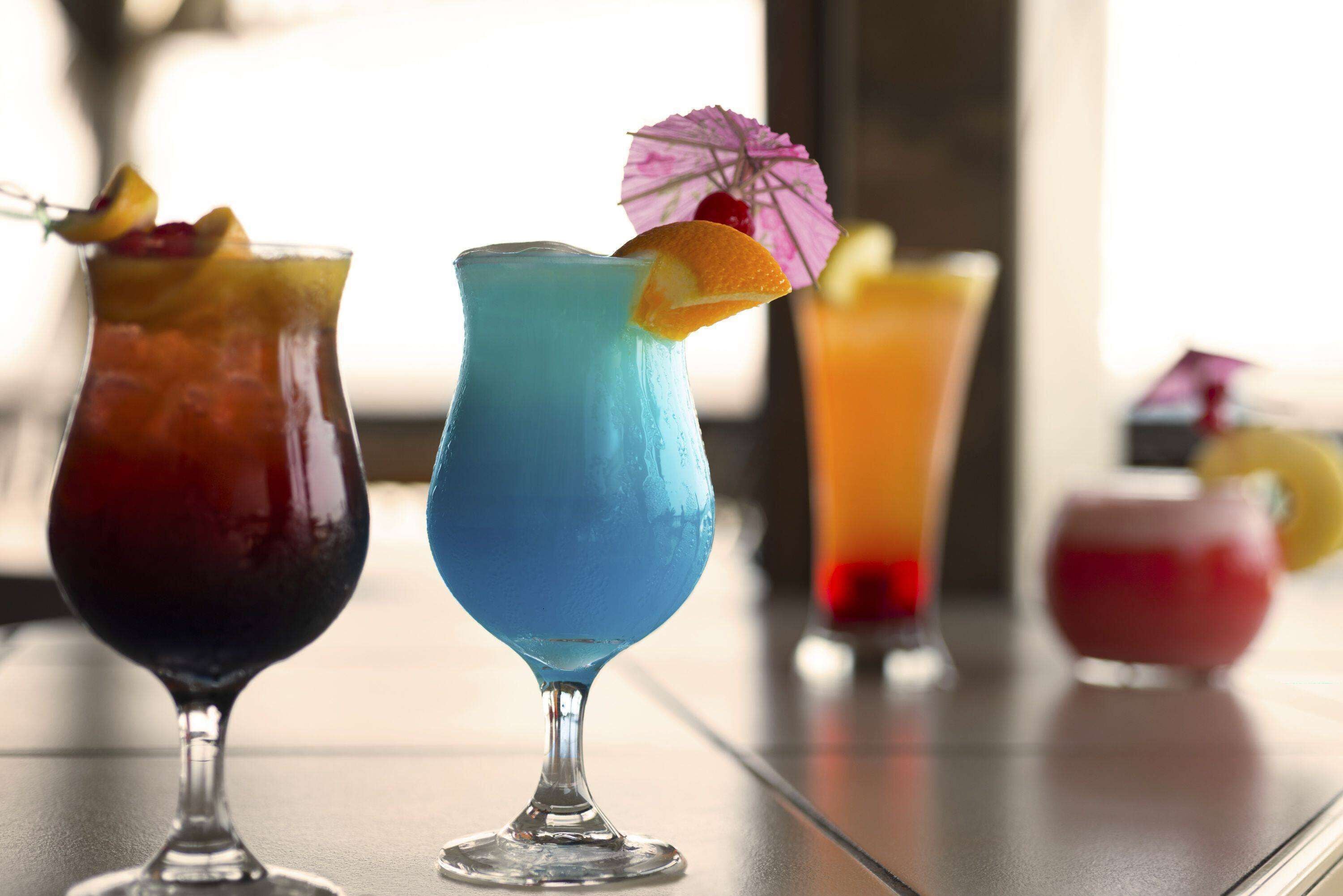 Baarissa on tarjolla monenlaisia värikkäitä cocktaileja, joista jokainen on koristeltu hedelmillä ja cocktail-varjostimella.