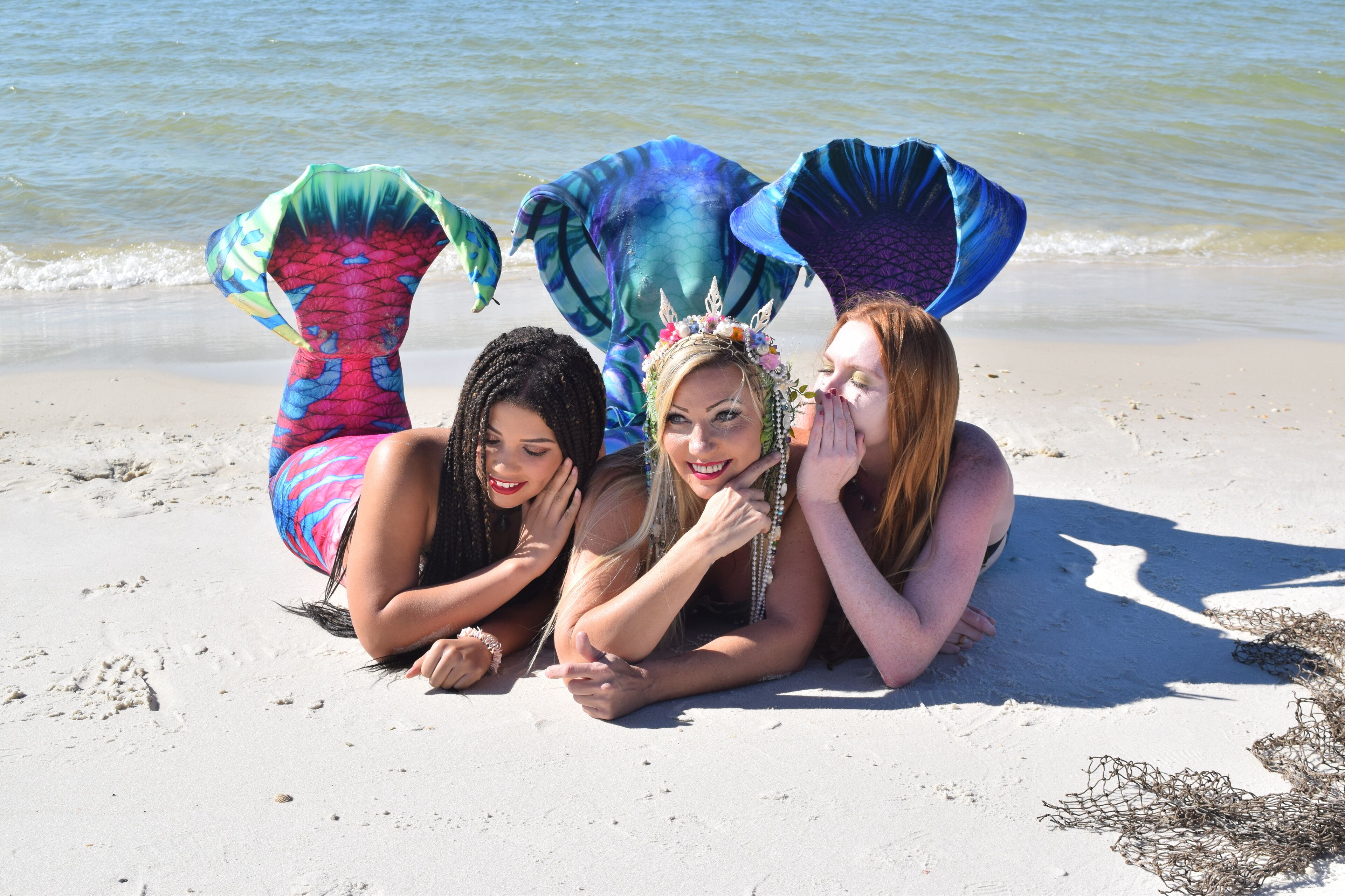 Three individuals on a sandy beach with a body of water in the background.