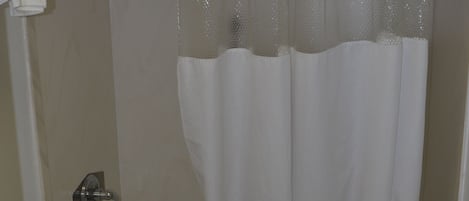 Un baño con bañera, inodoro y cortina de ducha.