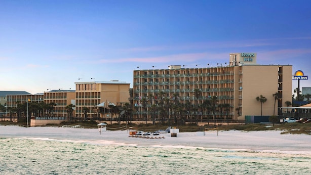 A hotel with multiple floors, a Days Inn sign, and a beach in the foreground. - Days Inn by Wyndham Panama City Beach/Beachfront Resort  (Panama City Beach)