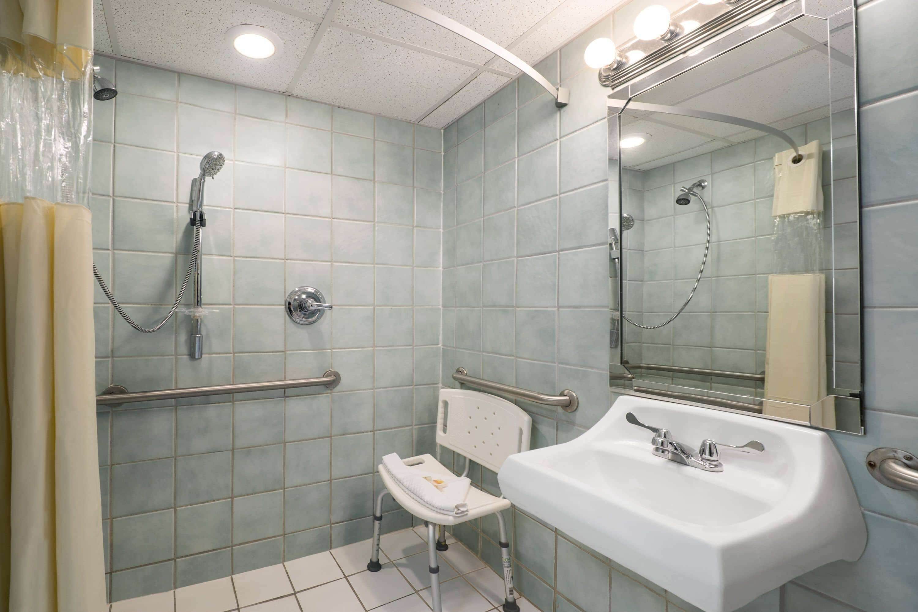 Un baño con lavamanos blanco, un espejo y ducha con cabezal de ducha de mano.