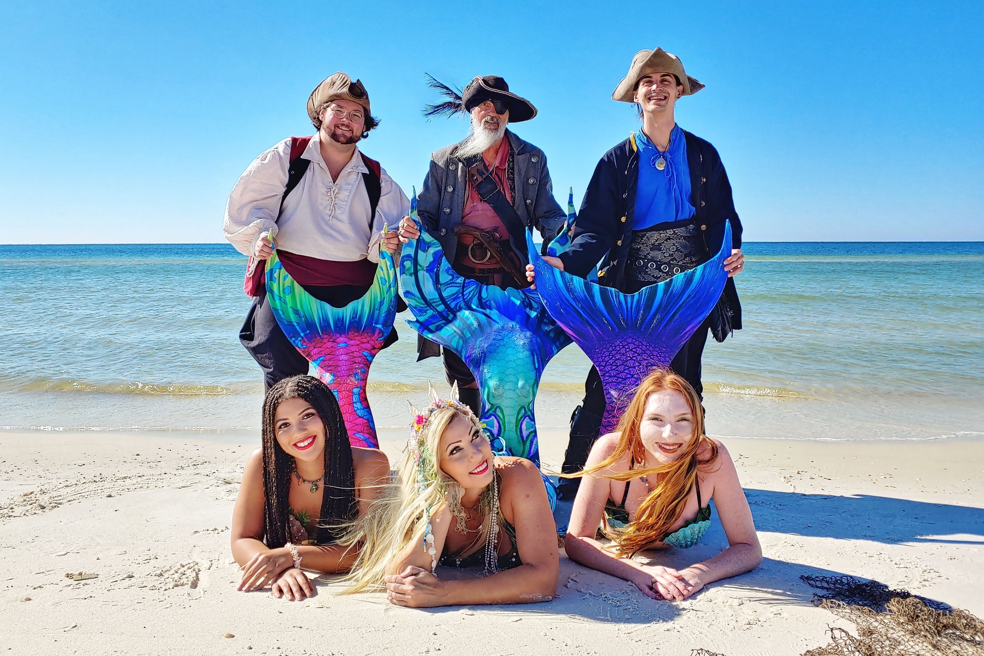 Een groep mensen op een strand met een heldere lucht en de oceaan op de achtergrond.