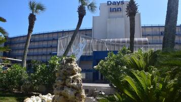A Days Inn hotel with a modern architectural design, featuring a prominent building sign and a decorative rock structure in the foreground.