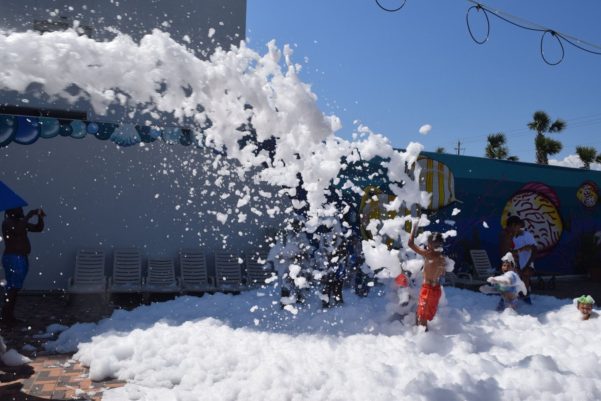 A beach scene with people playing in the water and foam.
