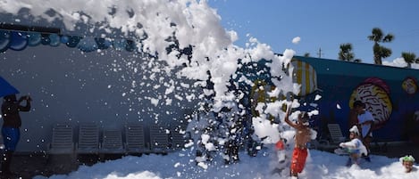 A beach scene with people playing in the water and foam.