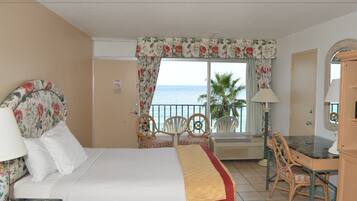 A hotel room with a bed, a desk, a chair, a lamp, and a view of the ocean.