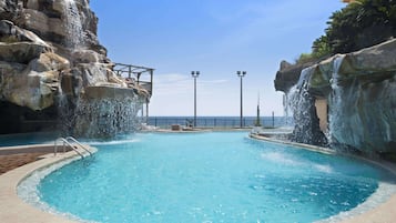 Relax by the serene pool surrounded by natural rock formations and a wooden bridge.