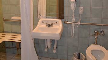 A bathroom with a sink, mirror, shower curtain, and a toilet.