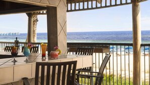 Un bar situé en bord de mer, offrant une vue sur l’océan et une jetée visible au loin.