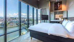 Un dormitorio moderno con una cama grande, televisión y vistas a la ciudad.
