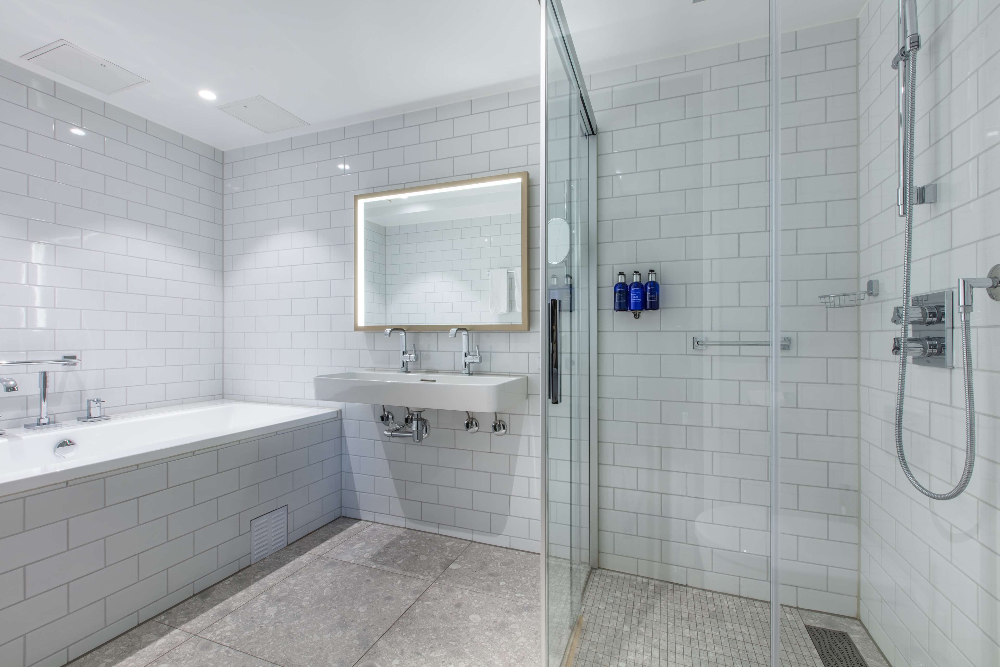A modern bathroom with a large white bathtub, a sink with a mirror, and a glass-enclosed shower area.