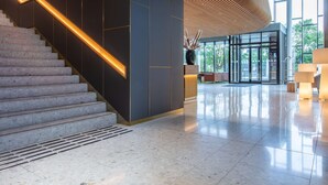 Un vestíbulo moderno con una escalera, un ascensor de vidrio y un amplio ventanal con vistas al exterior.