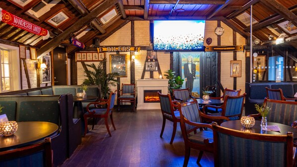 A cozy pub with wooden beams, a fireplace, and seating areas.