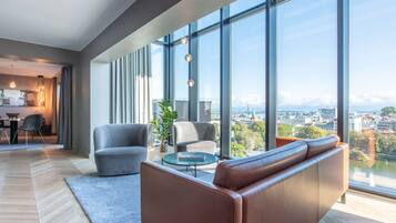 A modern living room with a large window, a sofa, a coffee table, and a dining area.