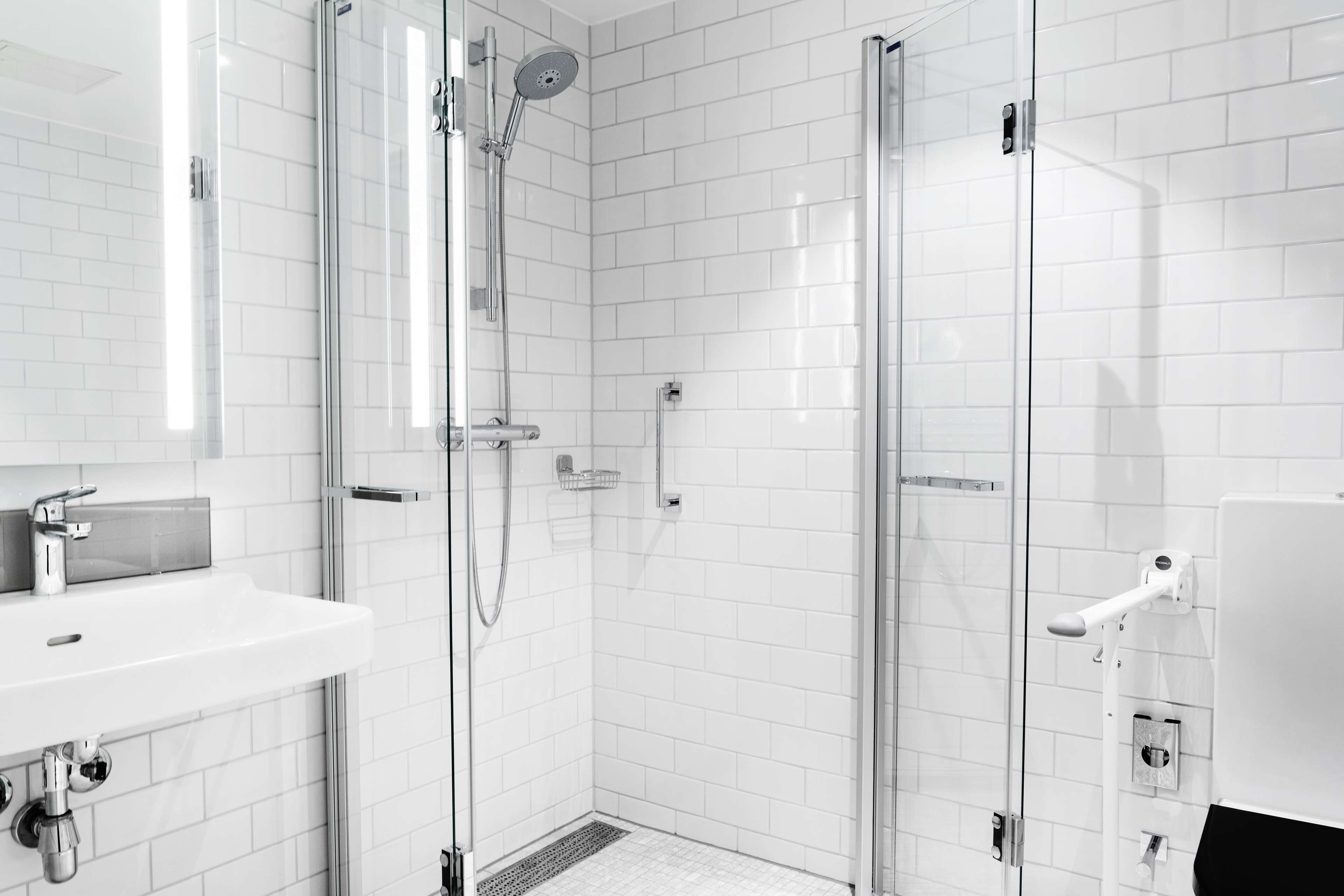 A modern bathroom with a glass-enclosed shower, a white sink, and a tiled floor.