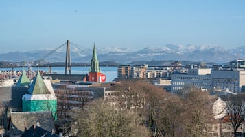 Eine Stadtansicht mit einer markanten Kirche, einer Brücke und schneebedeckten Bergen im Hintergrund.