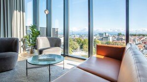 Una sala de estar moderna con un ventanal grande, un sofá, dos sillones y una mesa de centro.
