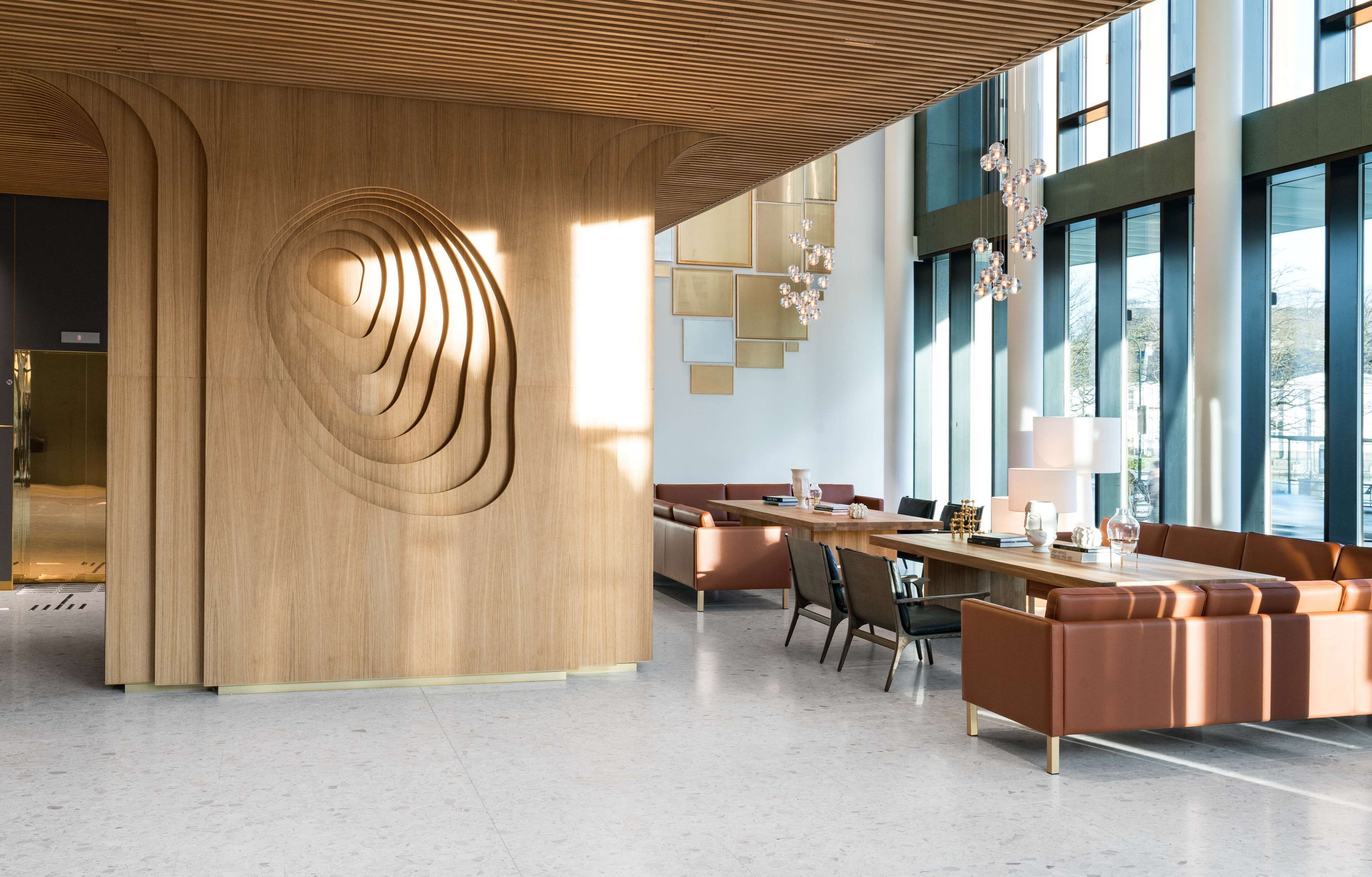 Un interior moderno con un muro decorativo de madera, una larga mesa de comedor y un área de estar con sofás y sillones.