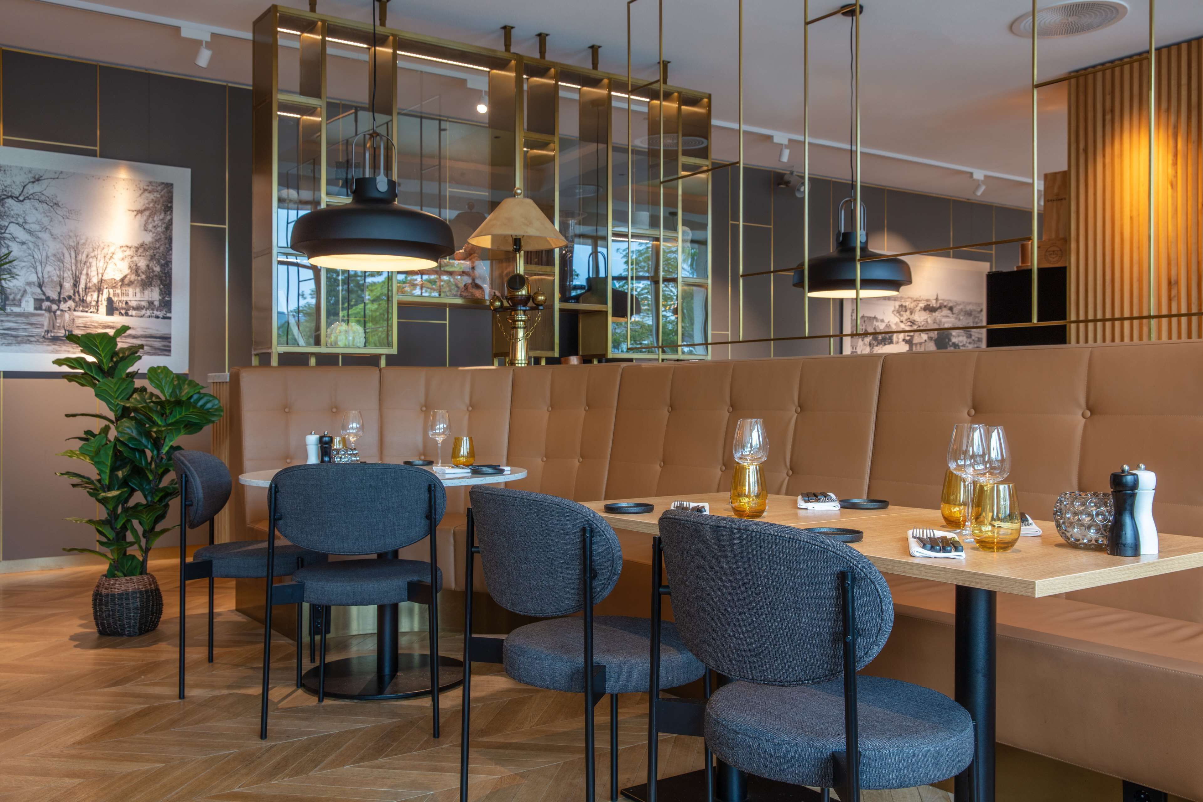 A modern dining area with a booth seating arrangement, a round table, and a large mirror.