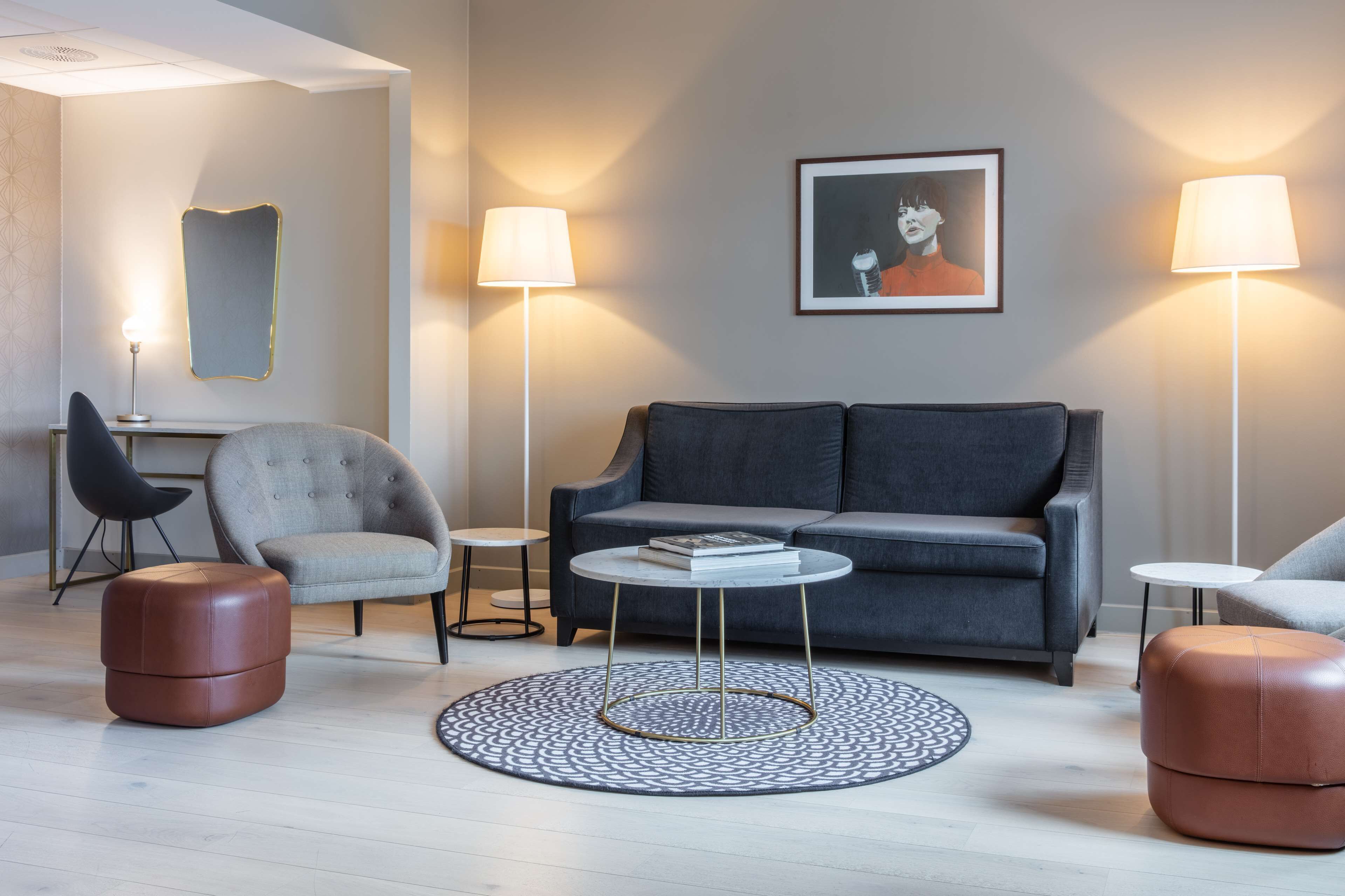 A modern living room with a grey sofa, two armchairs, a coffee table, and a round rug.