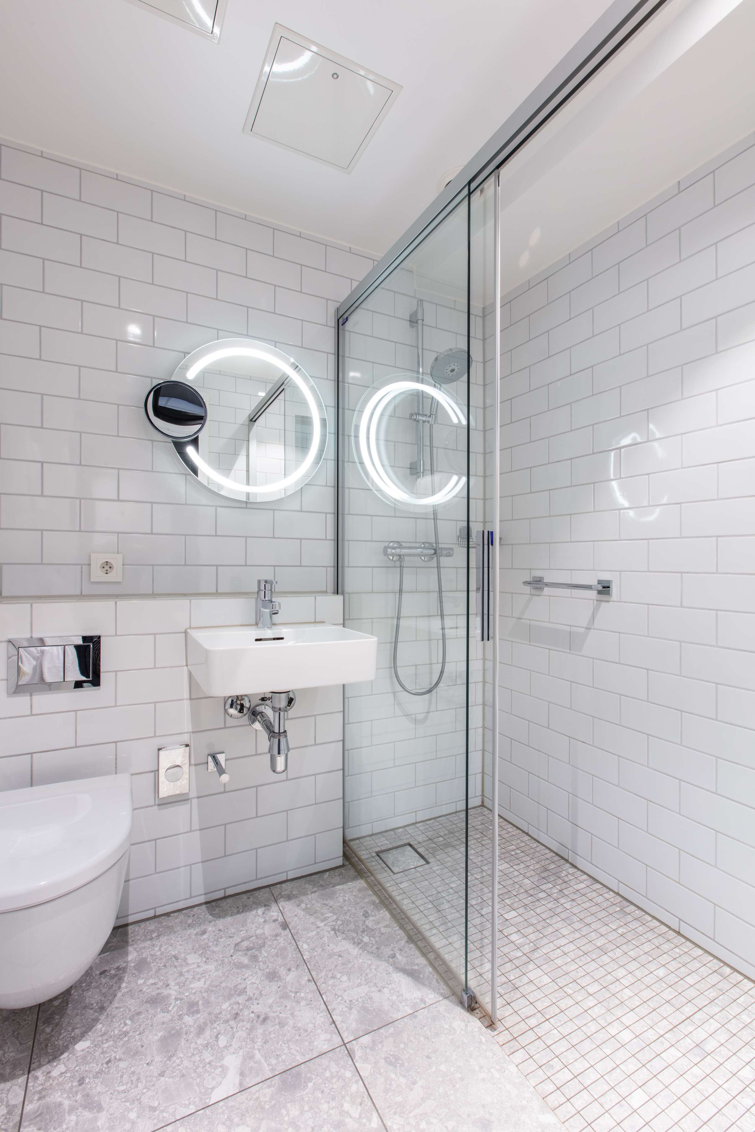 A modern bathroom with a glass shower enclosure, a white sink, and a toilet.
