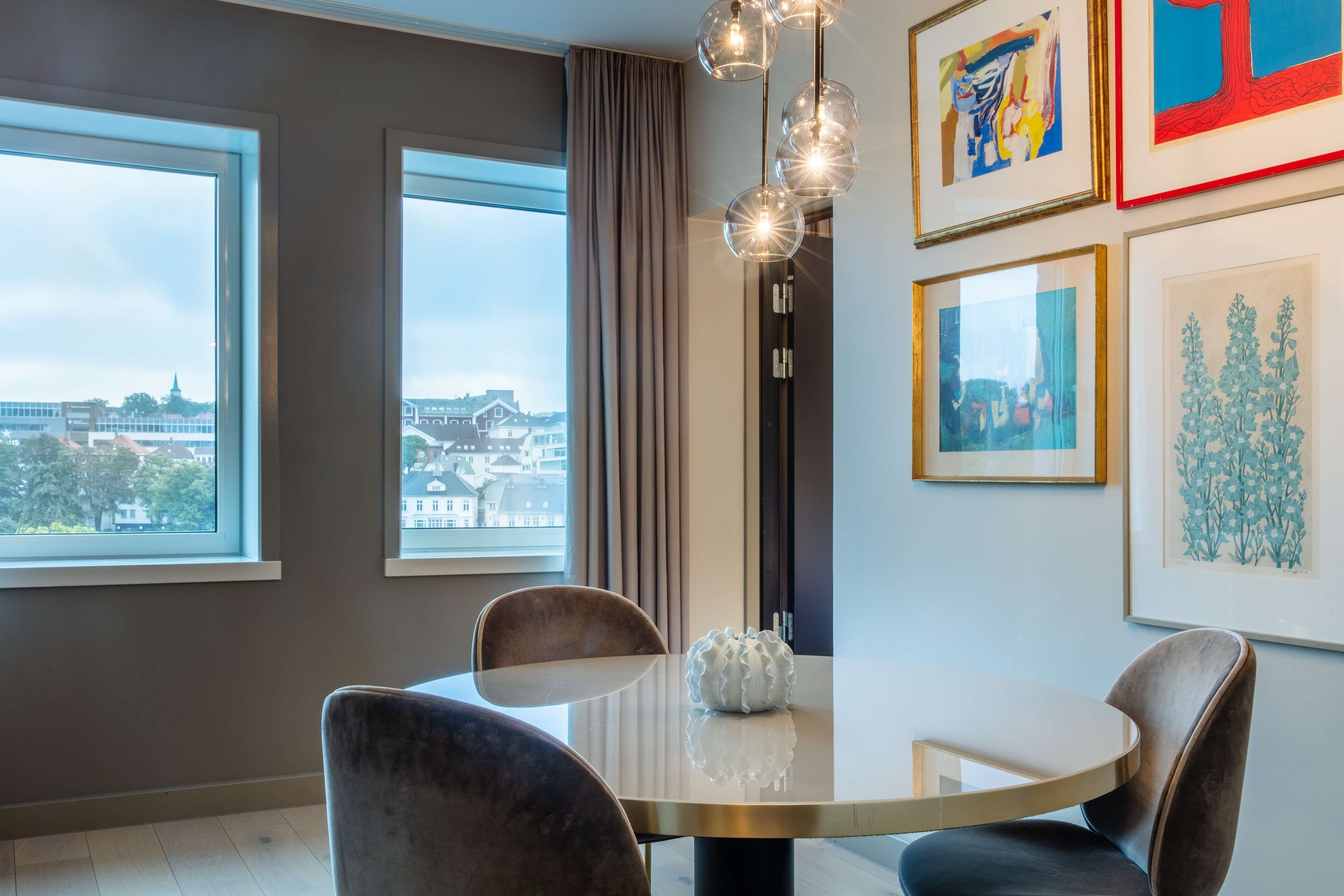 Un comedor moderno con una mesa redonda, cuatro sillas y un jarrón decorativo.