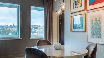 A modern dining area with a round table, four chairs, and a decorative vase.