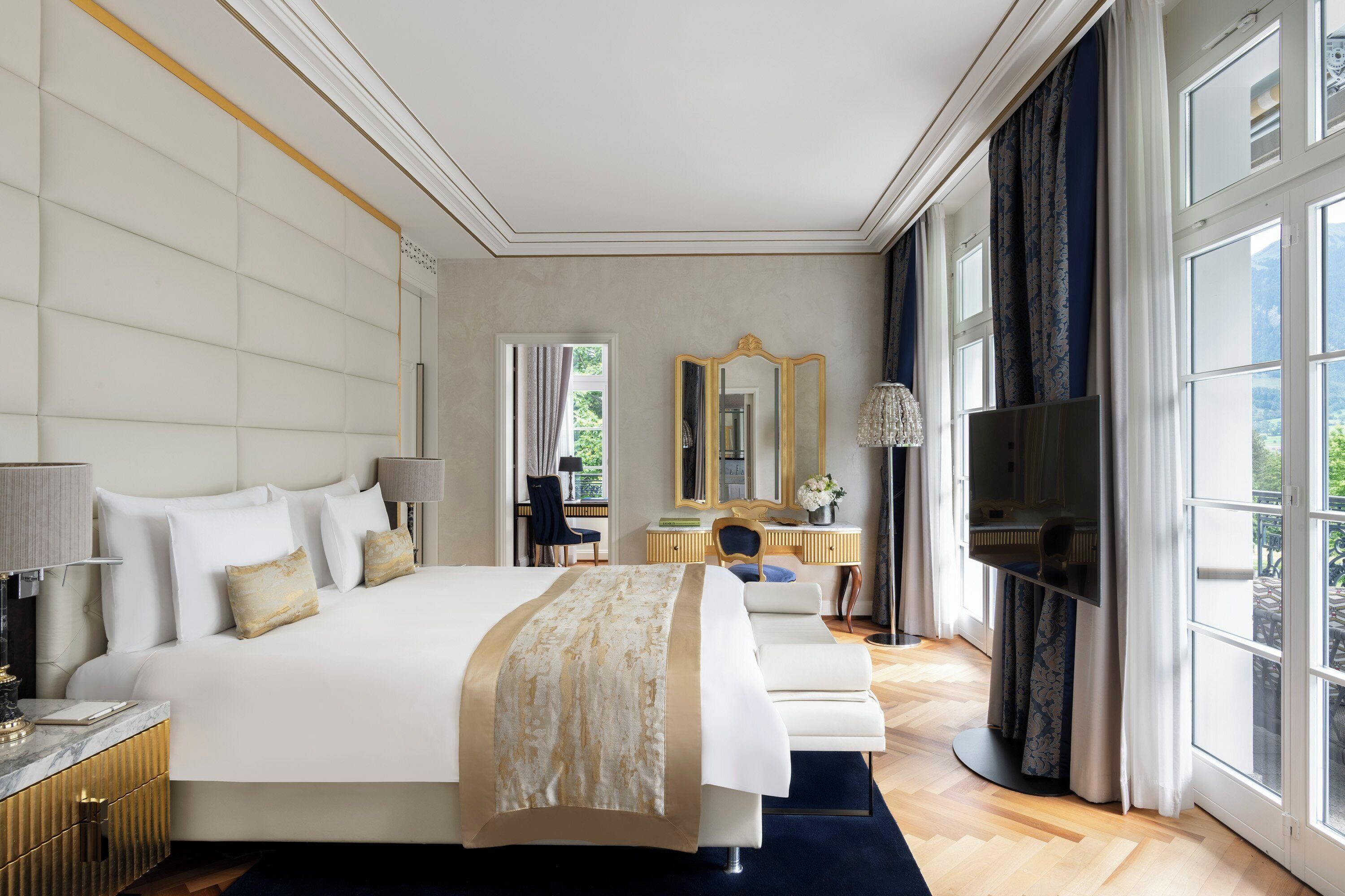 Une chambre spacieuse avec un grand lit, un bureau, une chaise, une télévision et une vue sur l’extérieur.