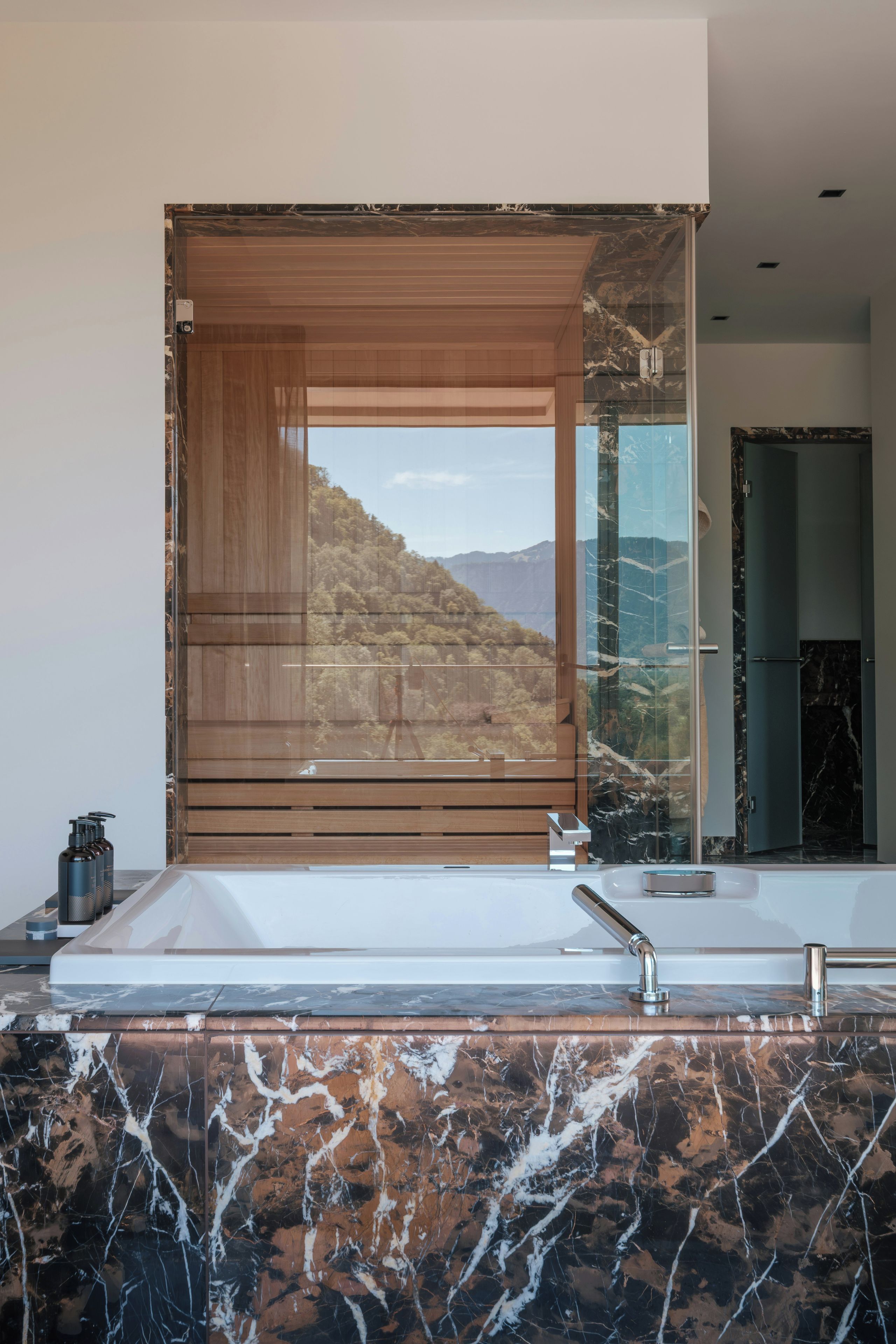 A bathroom with a large mirror, a bathtub, and a marble countertop.