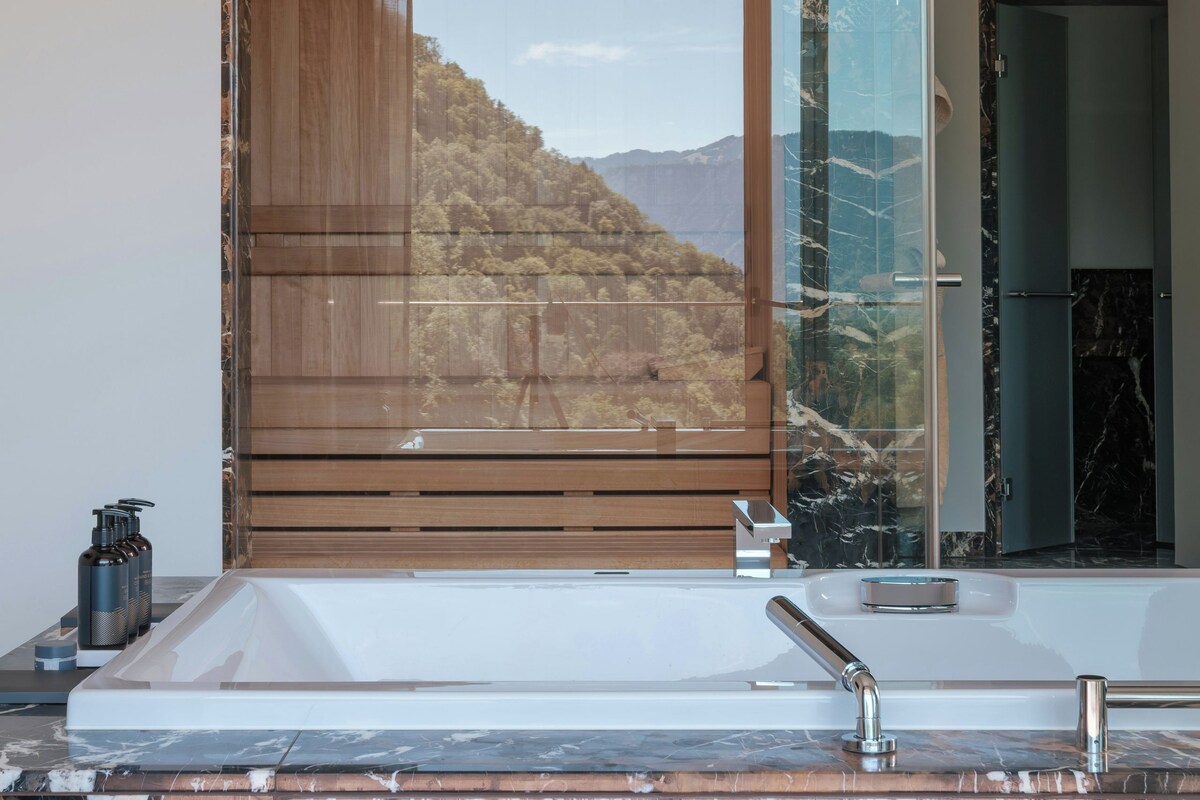 Un baño con un espejo grande, una bañera y una encimera de mármol.