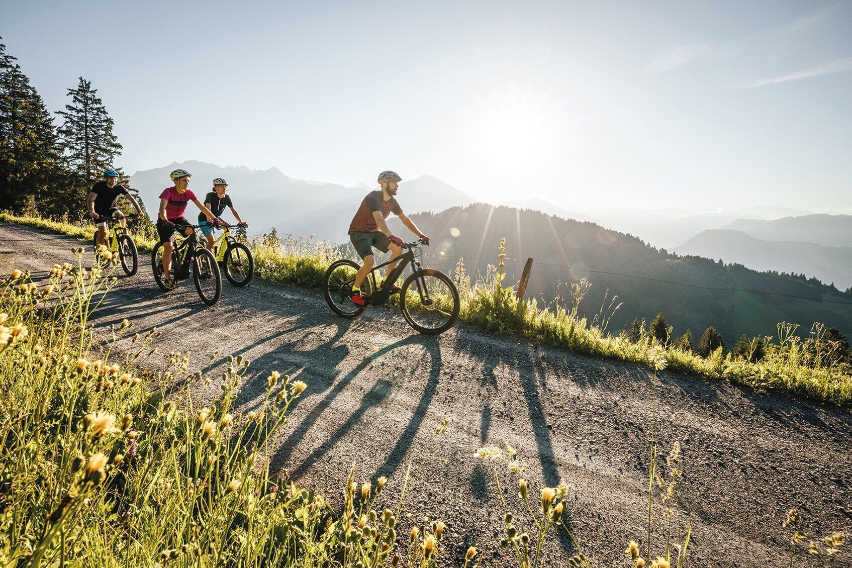 Un grupo de ciclistas en un camino de grava con montañas al fondo.