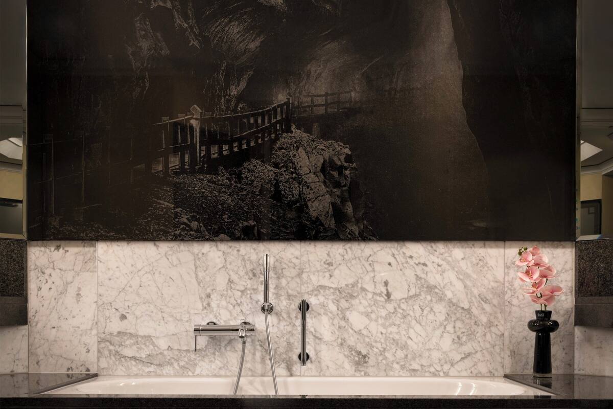 A bathroom with a large mirror, a marble sink, and a shower.