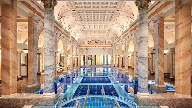 A large indoor swimming pool with marble columns and a high ceiling.