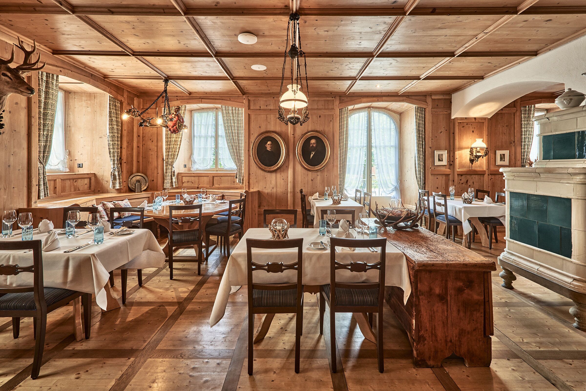 A restaurant with wooden interiors, multiple dining tables, and chandeliers.
