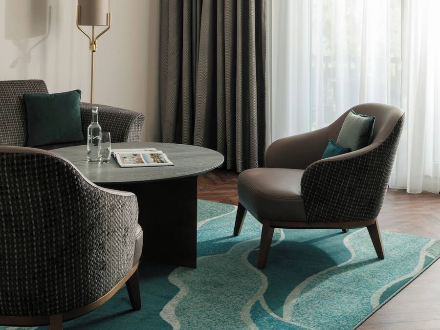 Une chambre d’hôtel moderne équipée d’un canapé, d’un fauteuil et d’une table basse avec des magazines.