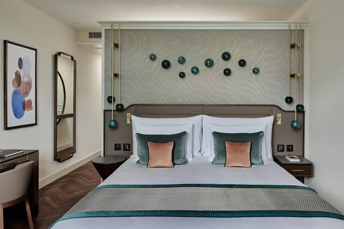 A hotel room with a large bed, two bedside tables, a desk, and a chair.