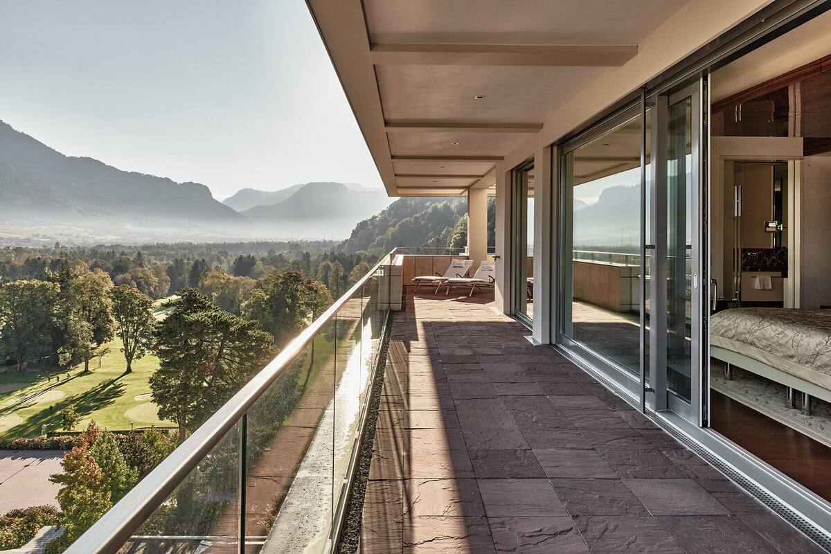 A balcony with a view of a golf course and mountains.