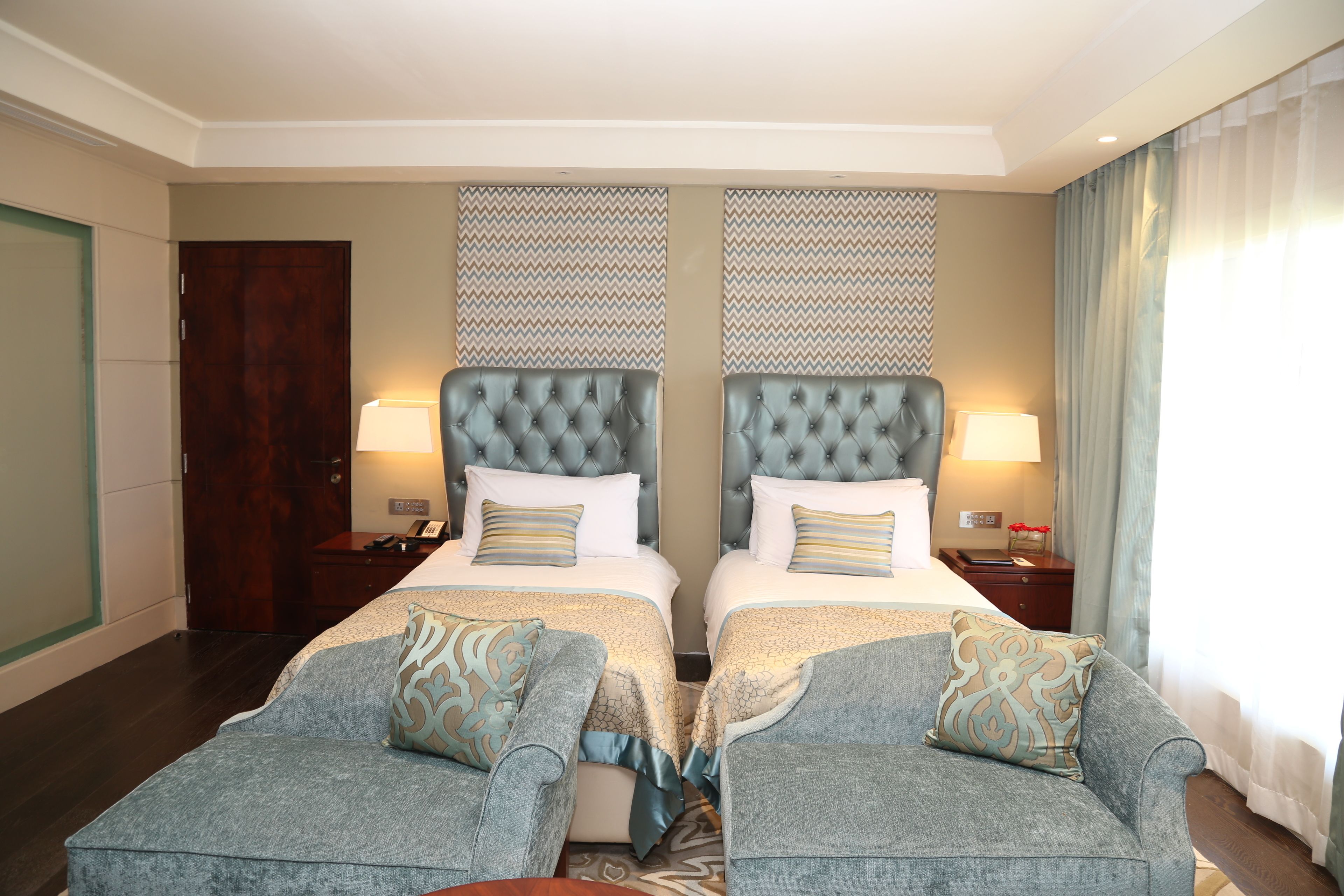 A hotel room with two beds, a sofa, a desk, and a nightstand.